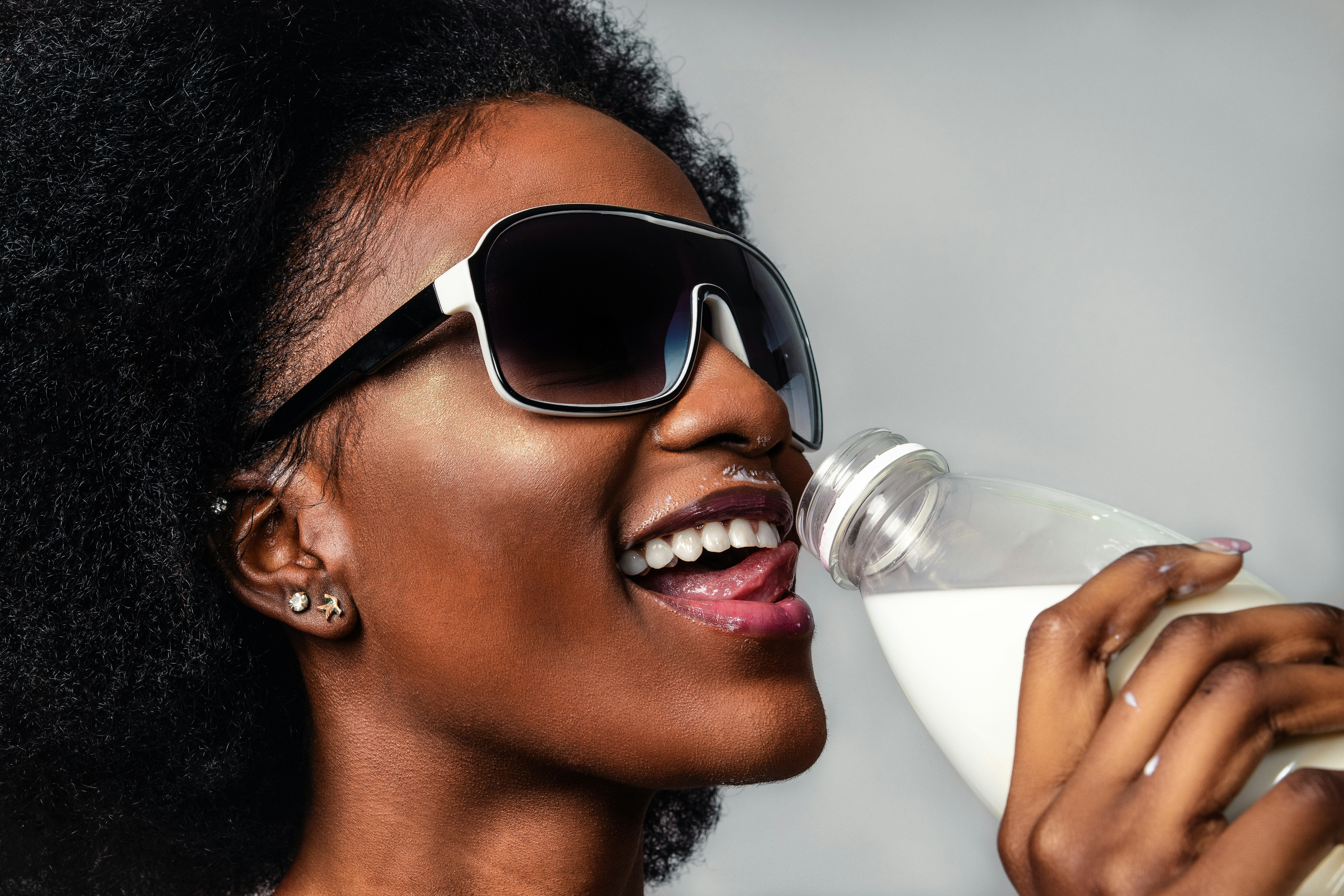 woman wearing black and white sunglasses drinking milk